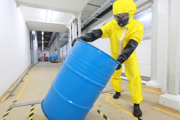 Employee in PPE moving chemical drum