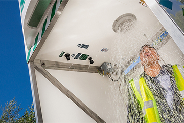 Male worker in high vis under an activated emergency tank shower